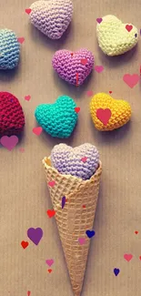 Wallpaper of colorful crocheted hearts in a cone on a beige background.