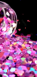 Heart confetti spilled onto black background, creating a colorful and vibrant display.