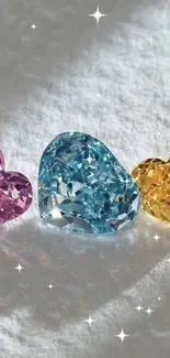 Three heart-shaped gemstones in pink, blue, yellow on a white background.