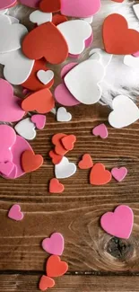 Colorful hearts scattered on a wooden background for mobile wallpaper.