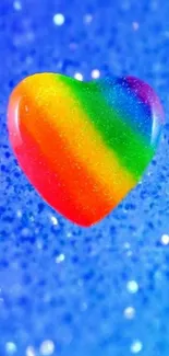 Rainbow heart on blue glittery background.