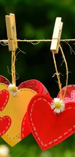 Colorful hearts and daisies on a clothesline with green backdrop.