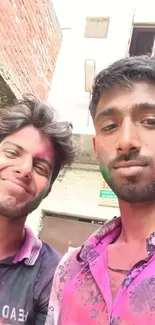 Two friends enjoying Holi with colorful powders on their faces.