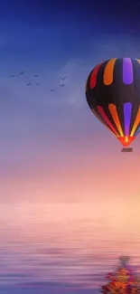 Hot air balloon over serene water at sunset.