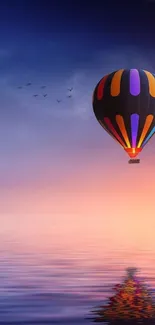 A colorful hot air balloon reflected in a calm sunset sky over water.