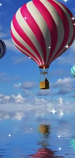 Three colorful hot air balloons reflecting on water under a blue sky.