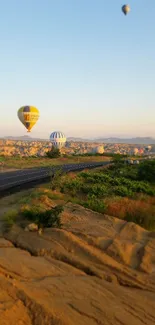 Hot air balloons floating above a scenic landscape at sunset.