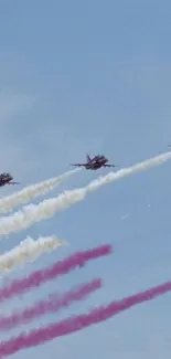 Jets in formation with colorful trails against a clear blue sky.