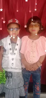 Two stylish kids posing with a red backdrop.