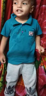 Child wearing blue shirt with floral background.