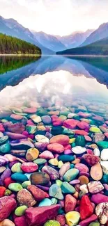 Colorful pebbles under a tranquil lake with mountain reflections.