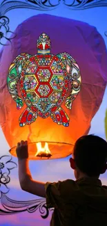 Child releases lantern with colorful turtle art against sunset sky.