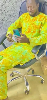 Person wearing colorful clothes seated with phone.