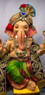 Colorful Lord Ganesha statue in decorative attire on wallpaper.