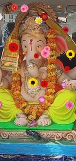 Ganesh idol surrounded by colorful flowers and vibrant decor.