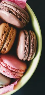 Assorted colorful macarons in a pastel green bowl.