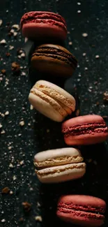 Colorful macarons aligned on a textured dark background in a vibrant mobile wallpaper.