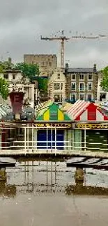 Colorful market stalls reflecting on wet ground under cloudy sky.