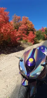 Motorcycle on road with vibrant autumn trees and blue sky.