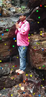 Person in pink shirt with confetti at waterfall.