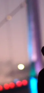 Silhouette against a colorful night bridge with vibrant lights.