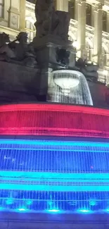 Colorful illuminated fountain at night with red and blue lights.