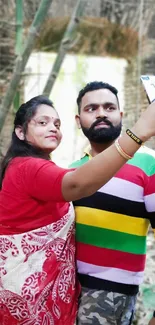 Couple takes colorful selfie outdoors with natural background.