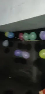 A string of colorful balloons on a dark wall for a lively party atmosphere.