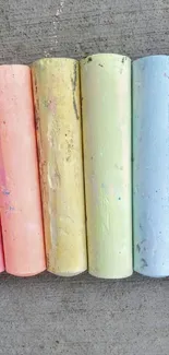 Six pastel chalk sticks on a concrete background.