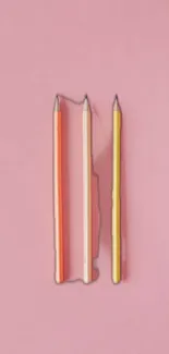 Three colorful pencils on a pink background wallpaper.