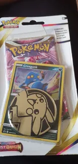 Pokemon card pack featuring Croagunk and colorful coin on display.