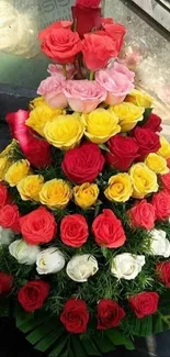 Pyramid of colorful roses arrangement with green leaves.