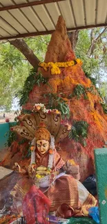 Colorful shrine with deity sculpture amidst nature.