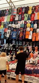 A busy market stall displays vibrant sports jerseys.