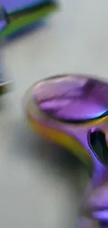 Close-up of a shiny, rainbow-colored fidget spinner on a mobile wallpaper.