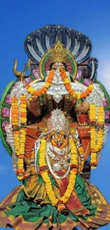 Colorful Indian deity statue under blue sky.