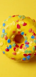 A vibrant yellow donut with colorful sprinkles on a matching background.