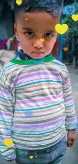 Young child in a striped shirt with colorful hearts overlay.