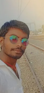 Person wearing colorful sunglasses on train tracks.