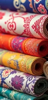 Colorful rolls of patterned textiles stacked closely.