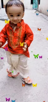 Toddler in red outfit with colorful butterflies.