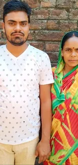 Traditionally dressed woman and man with a brick wall background.