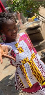 Young girl in colorful traditional attire smiling outdoors.