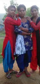 Three individuals in colorful traditional attire outdoors.