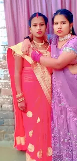 Two women in colorful traditional dresses posing together.