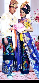 Couple in traditional attire with floral background, vibrant colors.