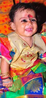 Baby in colorful traditional attire, smiling joyfully.