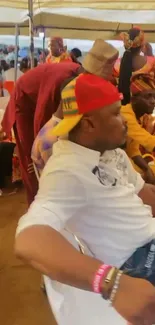 A man in vibrant cultural attire at a festive gathering.