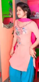 Woman in colorful traditional attire with pink background.