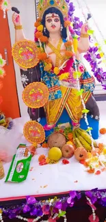 Vibrant idol decorated with colorful garlands and fruits for a festival celebration.